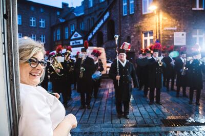 Grazyna Pawelczyk watches on from the front of her bakery in Nikiszowiec the local mines orchestra celebrate St Barbara's day. Rafal Wojczal for The National