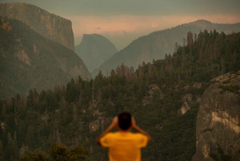 A tourist photographs Half Dome as smoke from the Ferguson Fire hangs over Yosemite National Park, California. Noah Berger/AP Photo