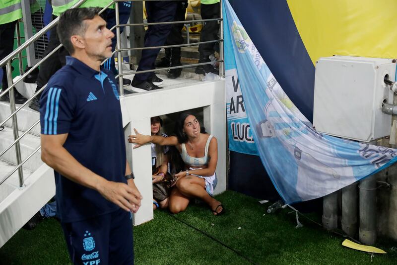 People take cover under stairs due to a clash between fans inside the Maracana stadium. EPA