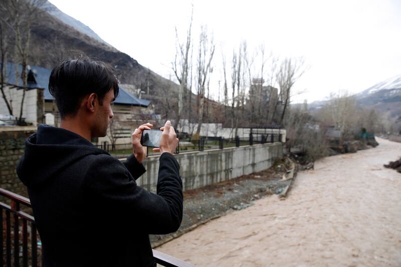 A man takes a picture of a river in Zardband.