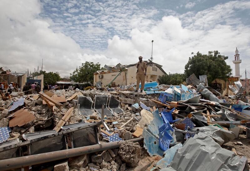 A police officer stands on top of the rubble of a destroyed building at the scene of a blast outside a district headquarters in the capital Mogadishu, Somalia Monday, Sept. 10, 2018.  At least four people are dead after a suicide bomber detonated an explosives-laden vehicle at the gate of a district headquarters in Mogadishu, a Somali police officer said Monday. (AP Photo/Farah Abdi Warsameh)
