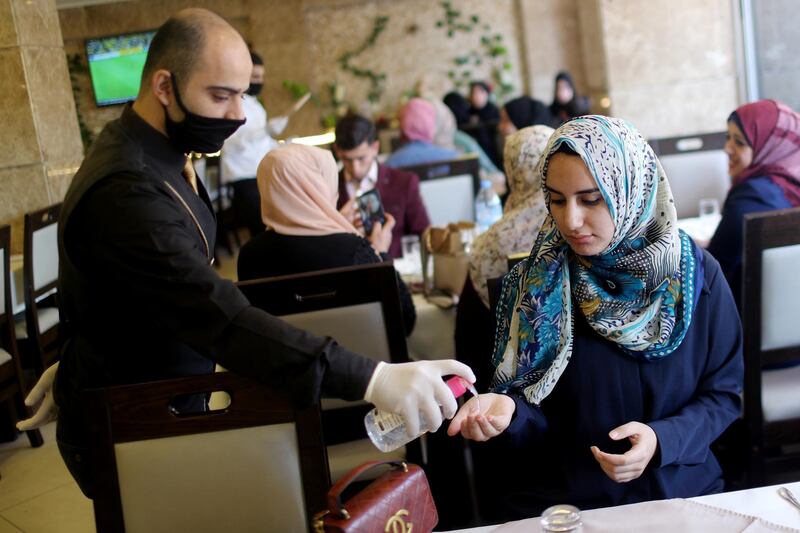 A waiter sanitises the hands of a customer in a restaurant as Palestinians ease the coronavirus disease restrictions, in Gaza City. Reuters