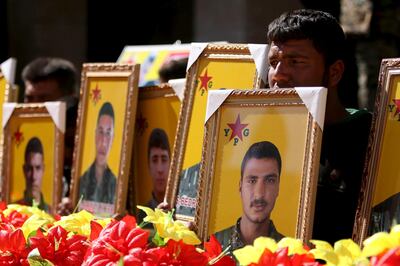 FILE PHOTO: Relatives carry pictures of fighters from the Kurdish People's Protection Units (YPG), who were killed when Islamic State militants attacked the town of Tel Abyad on the Turkish border at the weekend, during their funeral procession at Ras al-Ain city, in Hasakah province,  Syria March 2, 2016. REUTERS/Rodi Said/File Photo