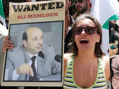 A protester with an image of Maj Gen Ali Mamlouk, a top Syrian security official, during a protest in Beirut in 2012. Reuters
