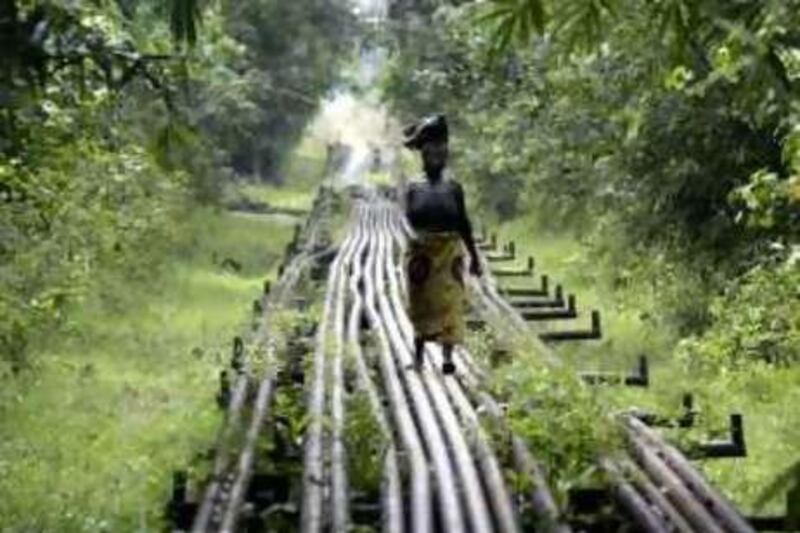 A woman walks along an oil pipeline near Shell's Utorogu flow station in Warri, Nigeria, Sunday, Jan. 15, 2006. Nigerian troops battled militia fighters in swamps around a Royal Dutch Shell oil platform that militants attacked at dawn Sunday, the third assault on Shell oil facilities in less than a week in the troubled region. Shell confirmed the attack on the Benisede oil platform in the southern oil-rich Niger Delta and said some of its staff had been injured and taken to hospital. The company also said it had begun evacuating personnel from vulnerable facilities in the region because of worsening security. (AP Photo/George Osodi)