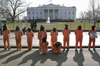 Human rights activists, hooded and wearing orange prison garb to represent prisoners at Guantanamo Bay, Cuba, protest in front of the White House. AFP