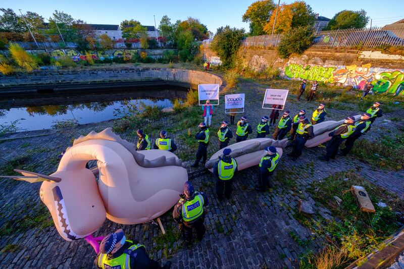 Police officers guarding an inflatable Loch Ness Monster at Govan Dry Dock after it was seized in a dawn raid in Glasgow. PA