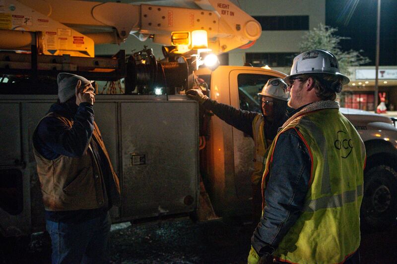 From left to right, electricity workers Brendan Waldon, Austin Strickland and Payton Merket share a conversation as they wait for a new work order after repairing a utility pole damaged by snow and ice in Odessa, Texas. AP