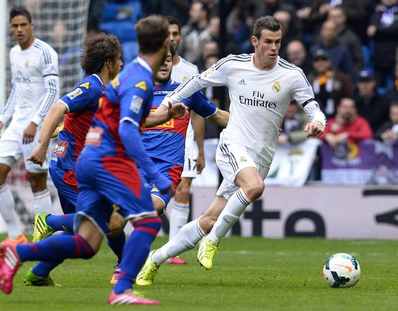 Real Madrid's Gareth Bale, right, dribbles through the Elche defence at the Santiago Bernabeu stadium on February 22, 2014. Gerard Julien / AFP