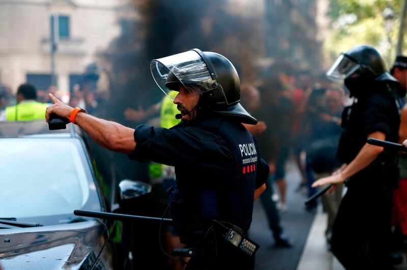 A police officer secures the area as the vehicle of an app-based ride-service goes through taxi drivers protesting outside a hotel during a strike in Barcelona.  AFP / Pau Barrena