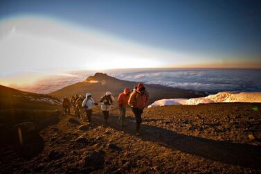 A team of hikers approach the summit of Mt. Kilimanjaro at sunrise. Getty Images