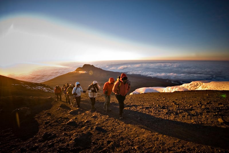 A team of hikers approach the summit of Mt. Kilimanjaro at sunrise. Getty Images