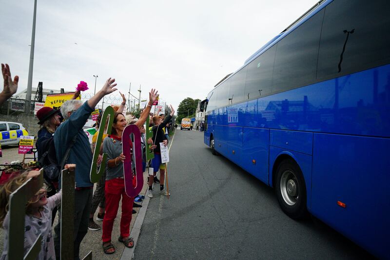 Locals wave to a coach believed to be carrying asylum seekers arriving at Portland Port. AP