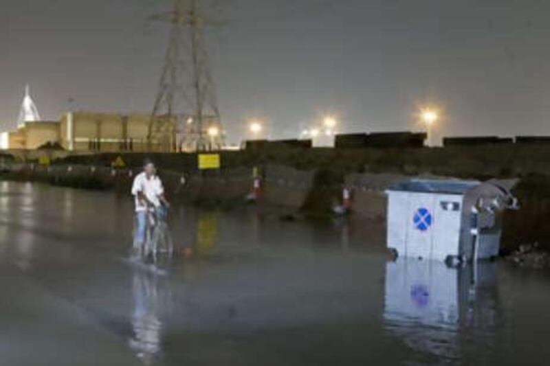 A cyclist rides through a flooded street behind The Mall of the Emirates in Dubai.