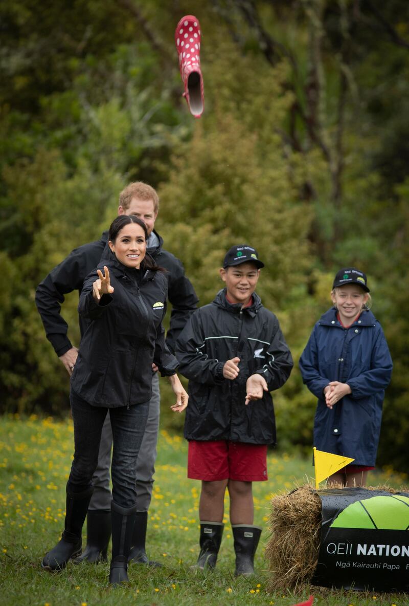 AUCKLAND, NEW ZEALAND - OCTOBER 30: Prince Harry, Duke of Sussex and Meghan, Duchess of Sussex react during their gumboot throwing competition after unveiling  a plaque after dedicating 20 hectares of native bush to the Queen's Commonwealth Canopy project at The North Shore Riding Club on October 30, 2018 in Auckland, New Zealand. The Duke and Duchess of Sussex are on their official 16-day Autumn tour visiting cities in Australia, Fiji, Tonga and New Zealand. (Photo by Greg Bowker/New Zealand Herald - Pool/Getty Images)