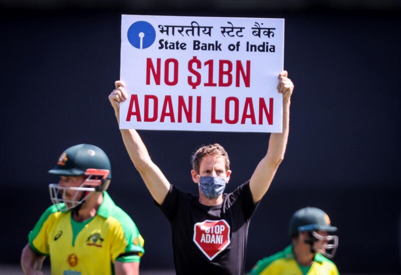 Australia's captain Aaron Finch, left, and teammate David Warner watch as a protester holds a sign during the first ODI against India at the Sydney Cricket Ground. AFP