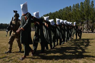 Afghan security forces escort suspected Taliban fighters as they are being presented in front of the media after an operation at the National Directorate of Security (NDS) headquarters in Herat on February 2, 2021. (Photo by HOSHANG HASHIMI / AFP)