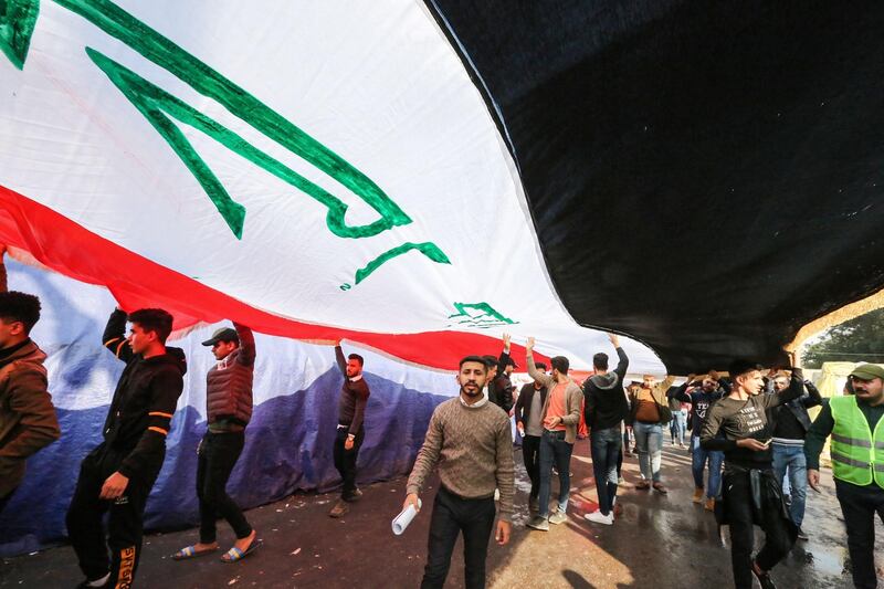 Protesters march with a giant Iraqi national flag during an anti-government demonstration in the capital Baghdad's central Tahrir Square on December 22, 2019.
  / AFP / SABAH ARAR
