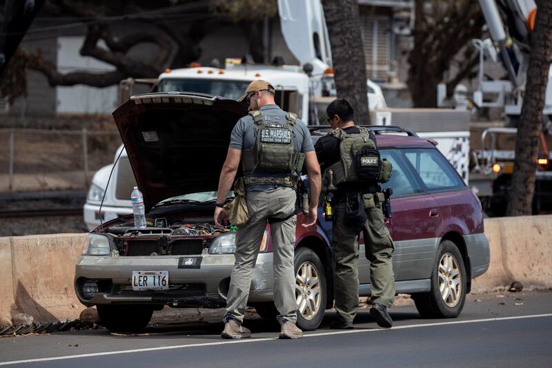 US marshals check an abandoned car in the ruins of a neighbourhood. EPA