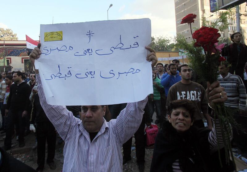 epa03006713 Egyptian Coptic Christians hold flowers and a placard reading in Arabic 'Coptic means Egyptianí during a protest after clashes between Coptic Christians and residents in the Shubra neighborhood, Cairo, Egypt, 17 November 2011. According to media reports, seven people were injured when clashes erupted between residents and Coptic Christians marching from the Shubra neighborhood towards the Egyptian State Radio and Television building in remembrance of the victims killed in clashes last October.  EPA/KHALED ELFIQI *** Local Caption ***  03006713.jpg