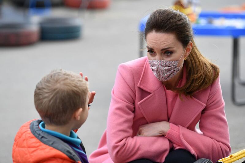 The Duchess of Cambridge watches as a child holds up five fingers to indicate his age. AP Photo