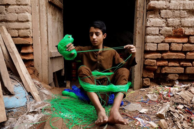A boy prepares nylon string to be used for weaving charpoy (rope bed) for sale at a workshop in Peshawar, Pakistan. Reuters