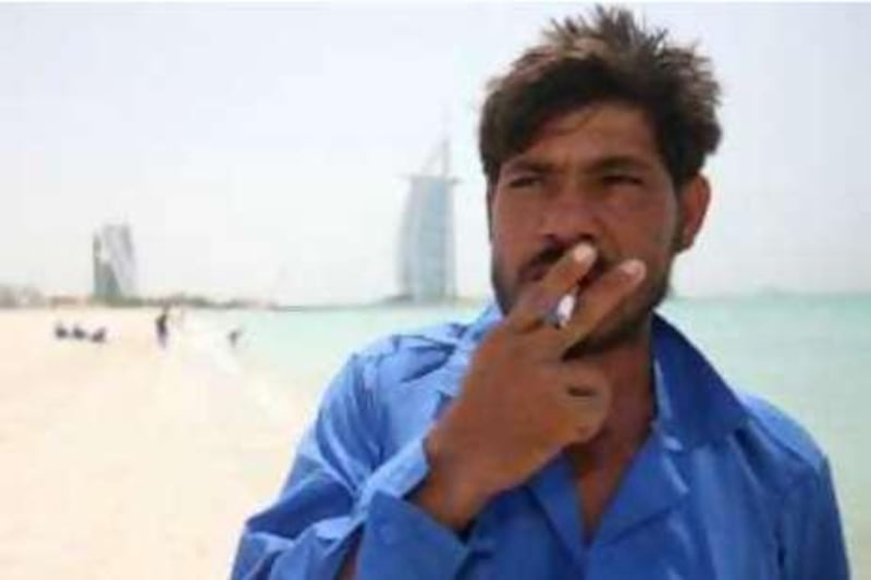 DUBAI, UNITED ARAB EMIRATES - August 7:  Sherbahader, a labourer from Pakistan, enjoys a cigarette during the mid-day break at the Jumeirah beach in Dubai on August 7, 2008.  (Randi Sokoloff / The National) *** Local Caption ***  RS007-SMOKING.jpg