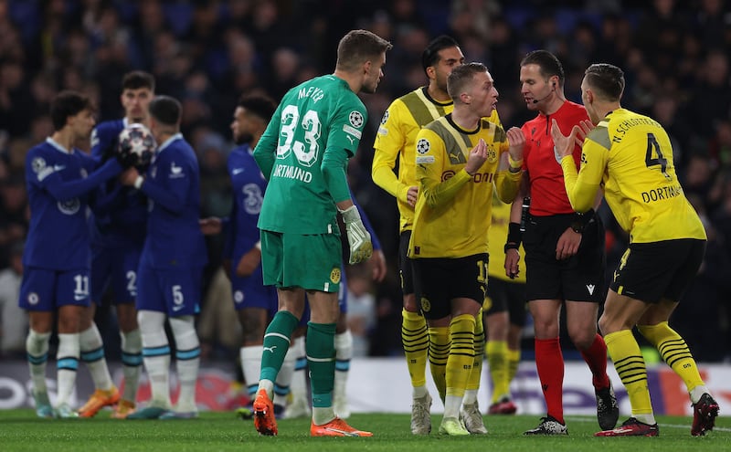Dortmund players surround referee Danny Makkelie after he ruled that Chelsea's German midfielder Kai Havertz should re-take his penalty after a VAR review. AFP