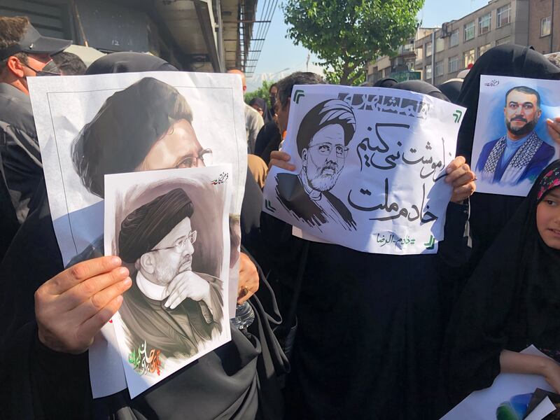 Mourners hold up portraits of Mr Raisi and Mr Amirabdollahian in Tehran. EPA