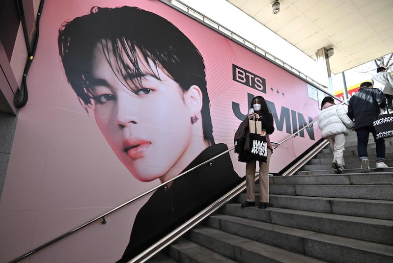 A woman takes a selfie in front of a big photo of Jimin, a member of BTS, at a subway station near Jamsil Olympic Stadium in Seoul. AFP