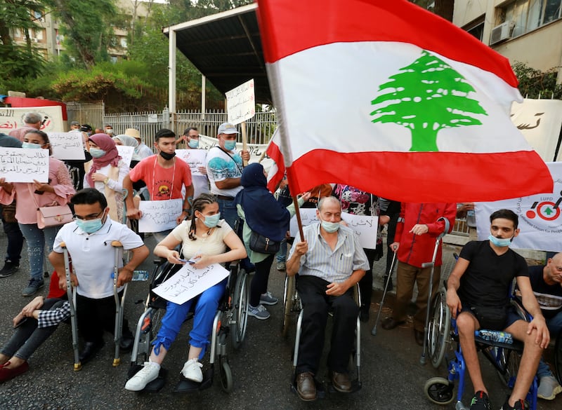 A man in a wheelchair flies a Lebanese flag during a protest demanding justice for the victims of last year's Beirut port blast.