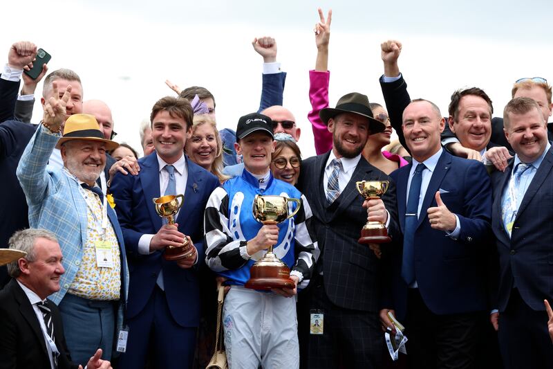 Jockey Mark Zahra, centre, holds his trophy as he celebrates with connections after winning the Melbourne Cup horse race on Gold Trip in Melbourne, Australia. AP Photo