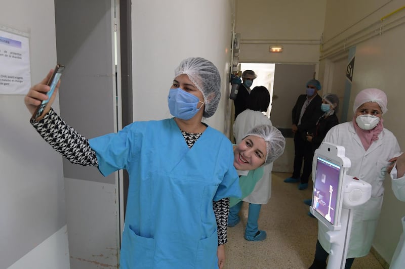 The medical staff at the Mami hospital interact with a robot, manufactured by a Tunisian company and donated to the hospital to support their efforts in combatting the coronavirus (COVID-19) pandemic, in a hallway in the hospital in the city of Ariana north of the Tunisian capital Tunis, on May 1, 2020.  / AFP / FETHI BELAID
