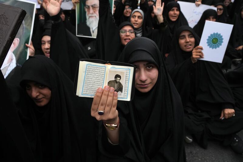 A demonstrator holds up the Quran and a portrait of Iranian supreme leader Ayatollah Ali Khamenei in a protest against Sweden in front of the Swedish embassy in Tehran. AP 