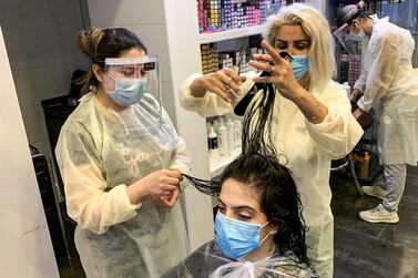 A hairdresser clad in face shield and mask cuts a client's hair at a women's salon in Saudi Arabia's capital Riyadh on June 21, 2020, as the country begins to re-open following the lifting of a lockdown due to the COVID-19 coronavirus pandemic. / AFP / RANIA SANJAR