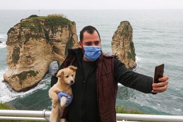 A man takes a selfie while carrying a dog in front of the Pigeons Rock in Beirut, Lebanon. Reuters