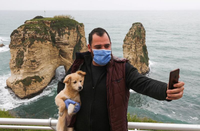 FILE PHOTO: A man takes a selfie while carrying a dog in front of the Pigeons Rock, during a countrywide lockdown to combat the spread of coronavirus disease (COVID-19) in Beirut, Lebanon March 30, 2020. REUTERS/Mohamed Azakir/File Photo