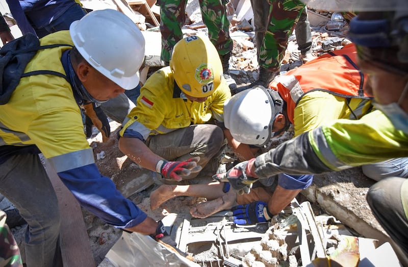 Rescue workers and soldiers carry a woman who was trapped in rubble since Sunday's earthquake. Antara Foto