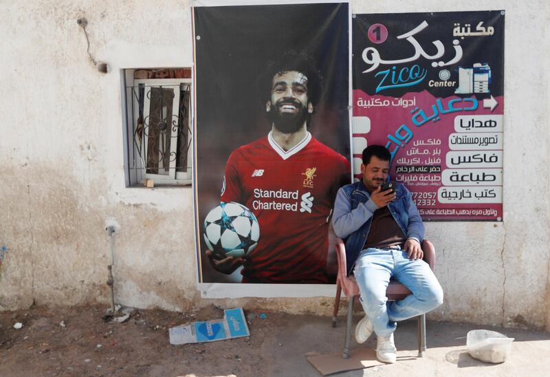 A man looks at his mobile phone near a picture depicting Liverpool's Egyptian forward Mohamed Salah, in front of his shop at the Dahab resort in the Sinai Peninsula, Egypt. Reuters