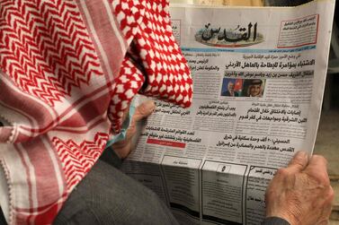 A Palestinian man reads the daily newspaper 'Al-Quds', with its front page headlines on events in neighbouring Jordan, in the occupied West Bank town of Hebron.  AFP 