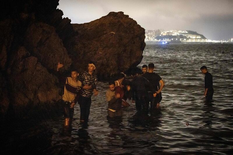 Moroccan migrants walk into shallow waters in the northern town of Fnideq. AFP
