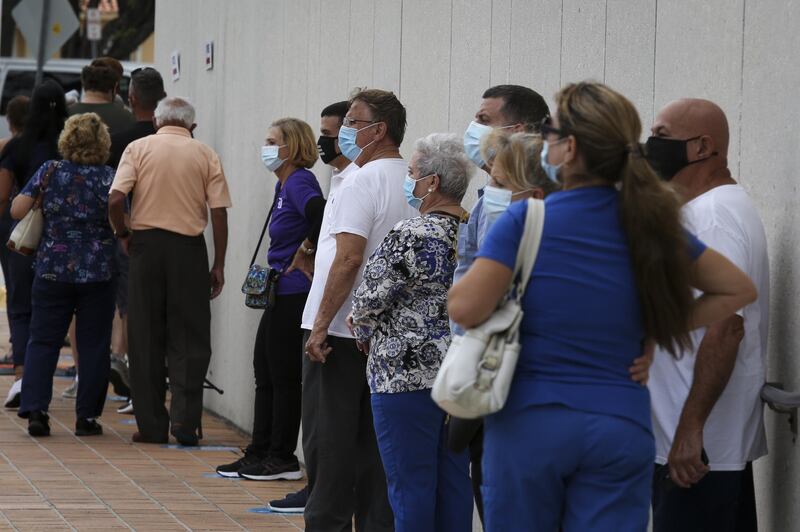 Voters wearing protective masks stand in line to cast ballots at an early voting polling location for the 2020 Presidential election in Miami, Florida, U.S., on Monday, Oct. 19, 2020. The Biden campaign and its supporters have booked $15.4 million worth of media advertising on Oct. 19, compared with $6 million booked by the Trump campaign and its backers, according to data by ad-tracking firm Advertising Analytics. Photographer: Marco Bello/Bloomberg