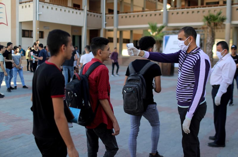 Palestinian students have their body temperature checked as they arrive to take high school exams in Gaza City. Reuters