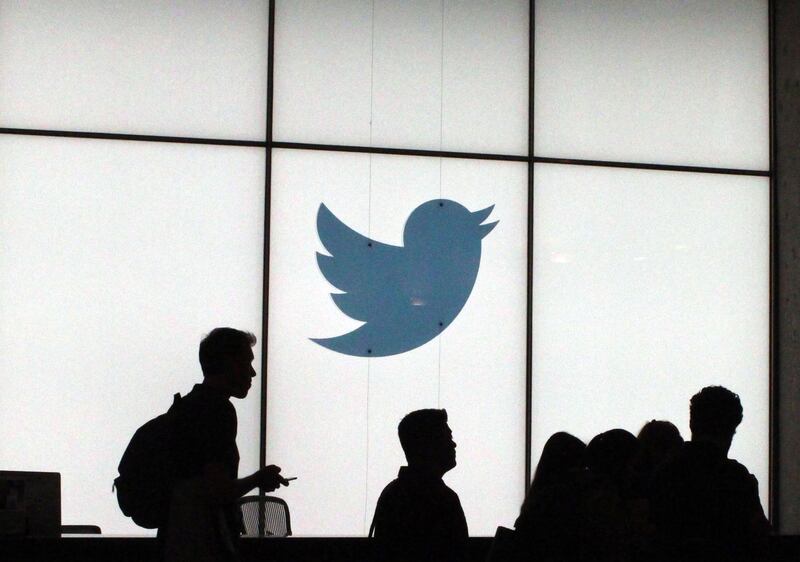 (FILES) In this file photo taken on August 13, 2019 employees walk past a lighted Twitter log as they leave the company's headquarters in San Francisco. Twitter on November 21, 2019, began letting users "hide" tweeted replies that could be seen as abusive or harassing in the latest effort by the online platform to create a more welcoming environment. The move is part of an effort to help users "feel safe and comfortable while talking on Twitter," head of product management Suzanne Xie said in a statement announcing the feature. / AFP / Glenn CHAPMAN
