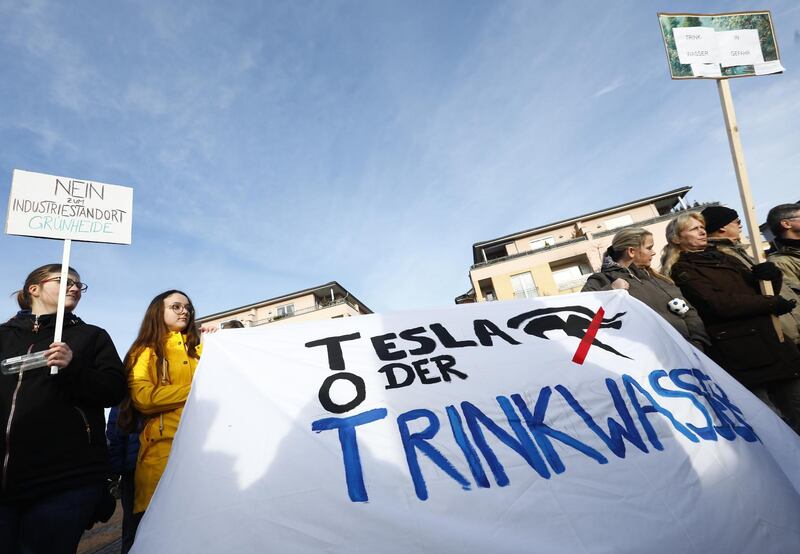 GRUENHEIDE, GERMANY - JANUARY 18: Protesters hold hold a banner reading, Tesla or drinking water,  as they demonstrate against the nearby planned new Tesla Gigafactory on the main square on January 18, 2020 in Gruenheide, Germany. They are criticising the felling of a forest to make way for the factory as well the projected increased water use. (Photo by Michele Tantussi/Getty Images)