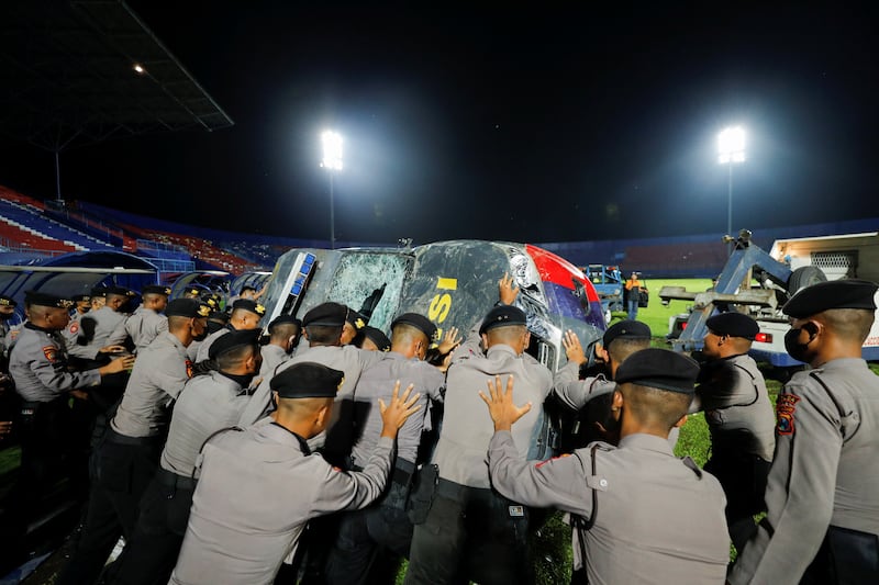 Police officers move a damaged vehicle out of the Kanjuruhan stadium. Reuters