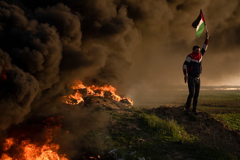 Palestinians burn tyres and wave the national flag during a protest against the raid. AP 