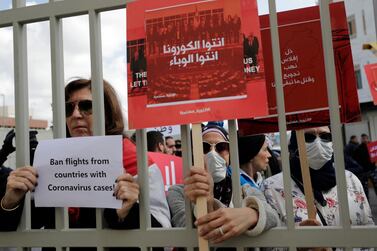 Anti-government protesters in front of Lebanon's health ministry on February 26 hold up banners in Arabic that read, "You are the coronavirus, you are the epidemic". Hassan Ammar / AP