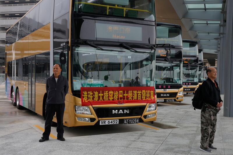 Passengers pose for a photograph in front of one of the shuttle buses. AP Photo