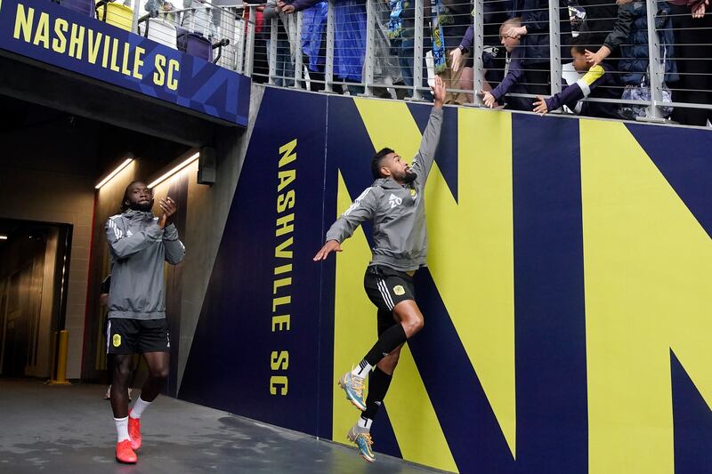 Nashville SC midfielder Anibal Godoy jumps to slap hands with a fan as he enters Geodis Park with teammate CJ Sapong for their first practice in their new stadium. AP